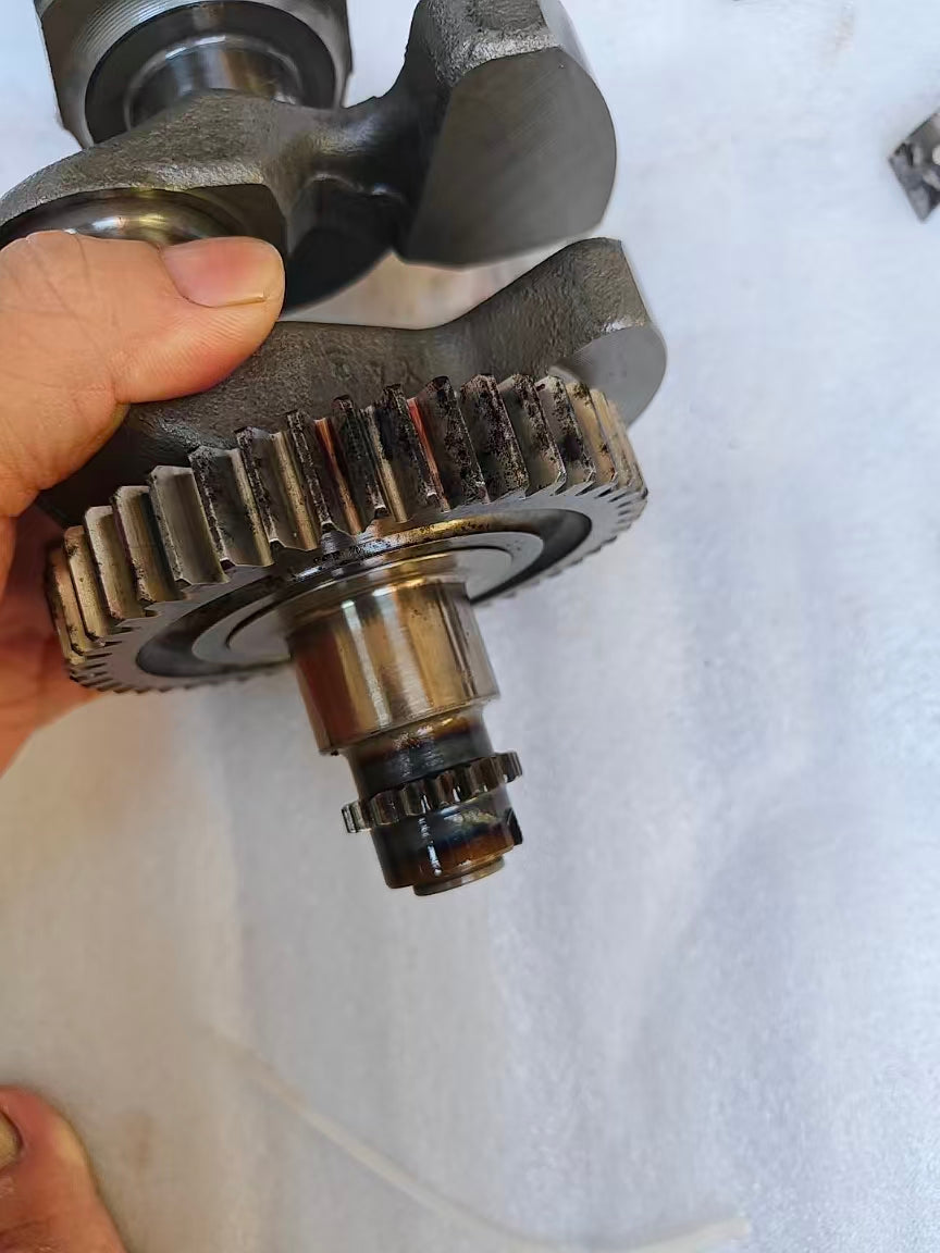 Close-up of Yamaha MT-09 crankshaft primary drive gear and splined pinion end, held in hand, some carbon staining on teeth