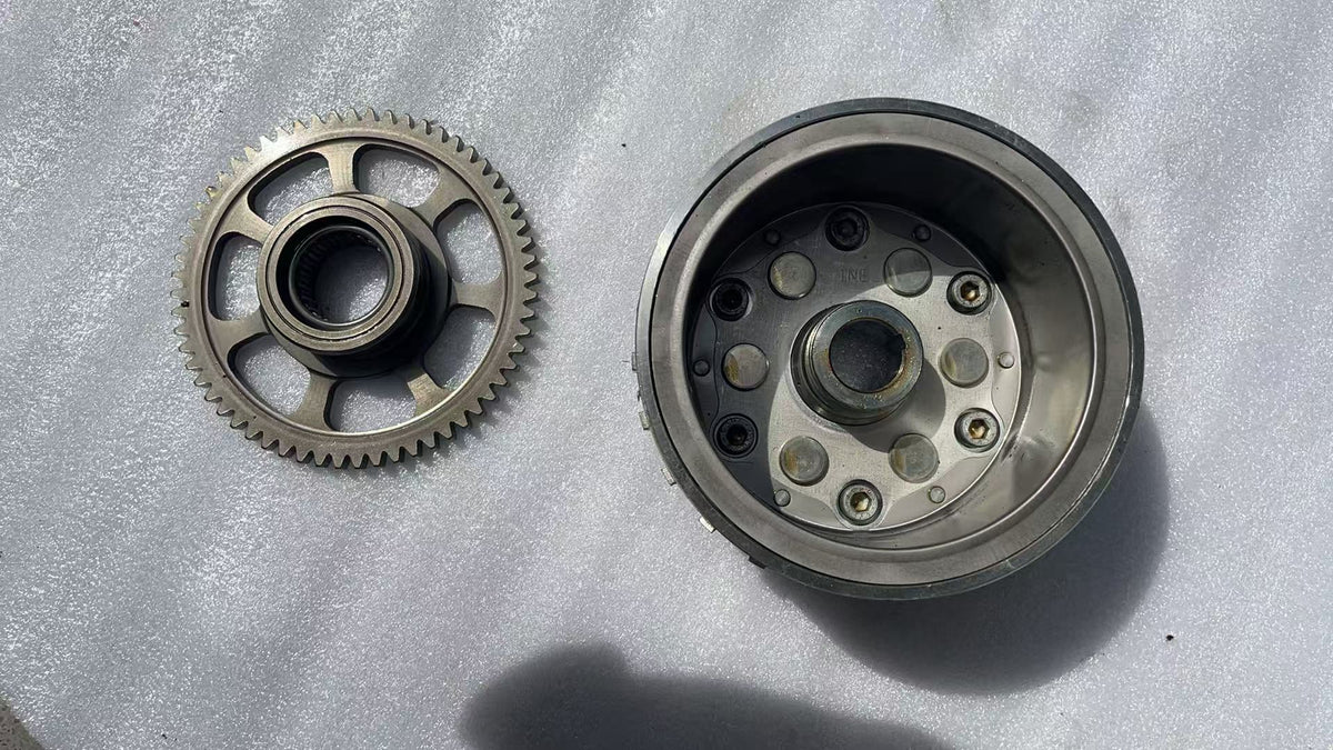 BMW G310R flywheel front face showing rotor teeth and center hub, clean used condition
