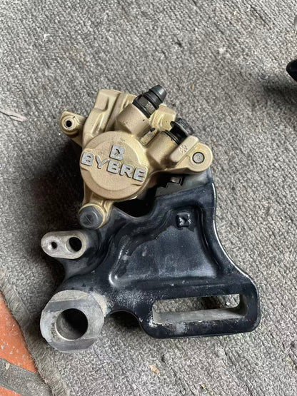 BMW G 310 R brake caliper front view showing pistons and mounting brackets, used condition