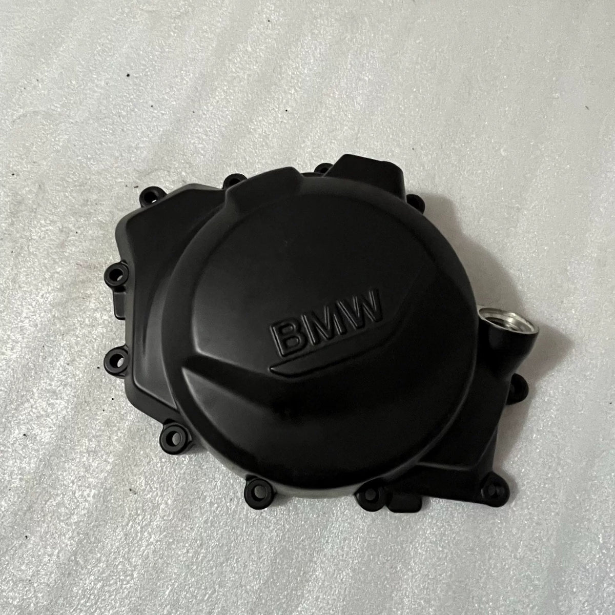 BMW F900R stator cover shown from front angle, black finish, bolt holes visible, clean condition