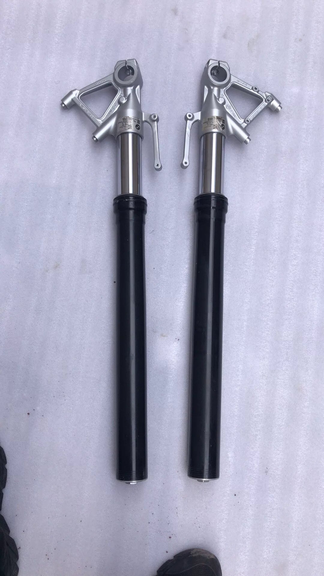 BMW S1000R fork leg pair, front view showing both chrome stanchions and lower legs standing upright