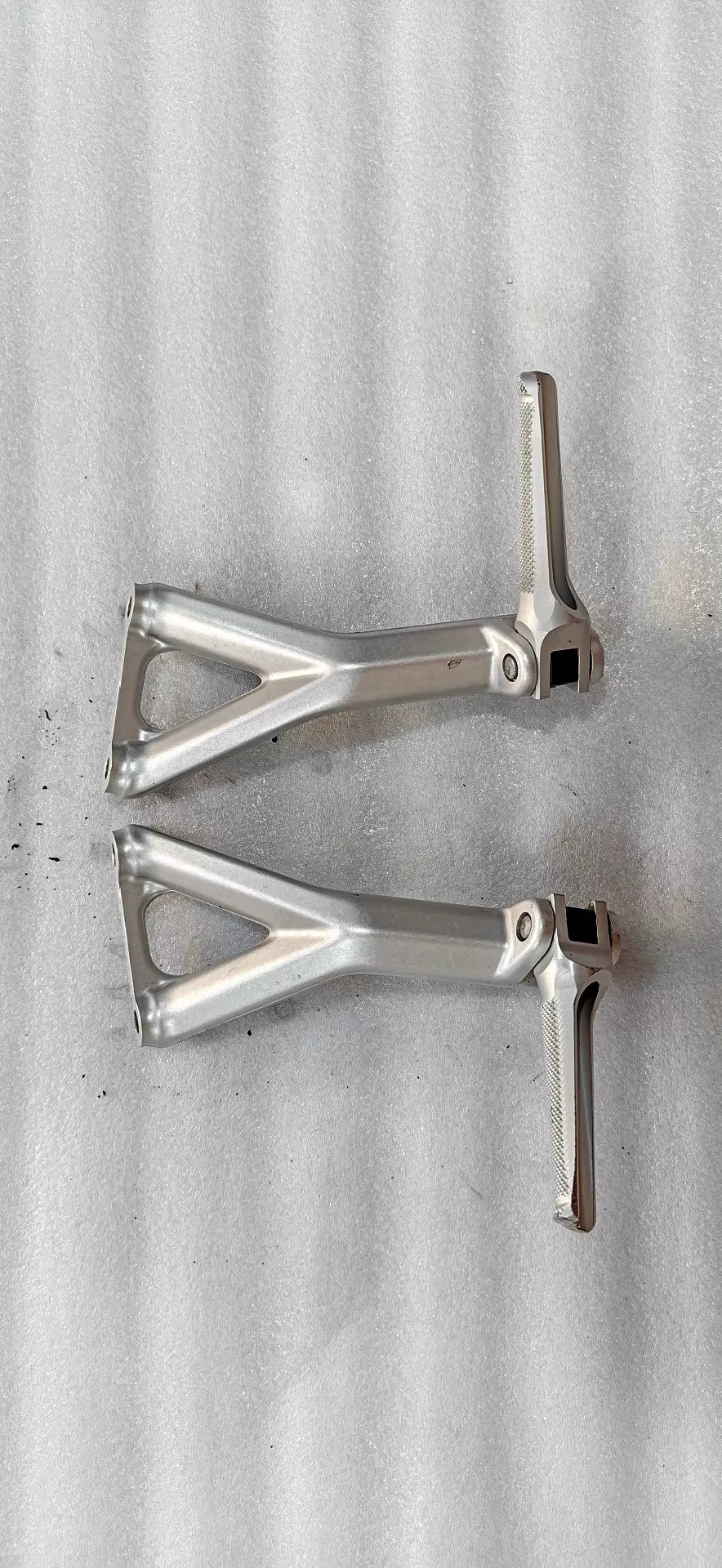 Ducati Panigale V4 rear sets footpeg bracket, angled top view showing machined aluminum construction and mounting hardware