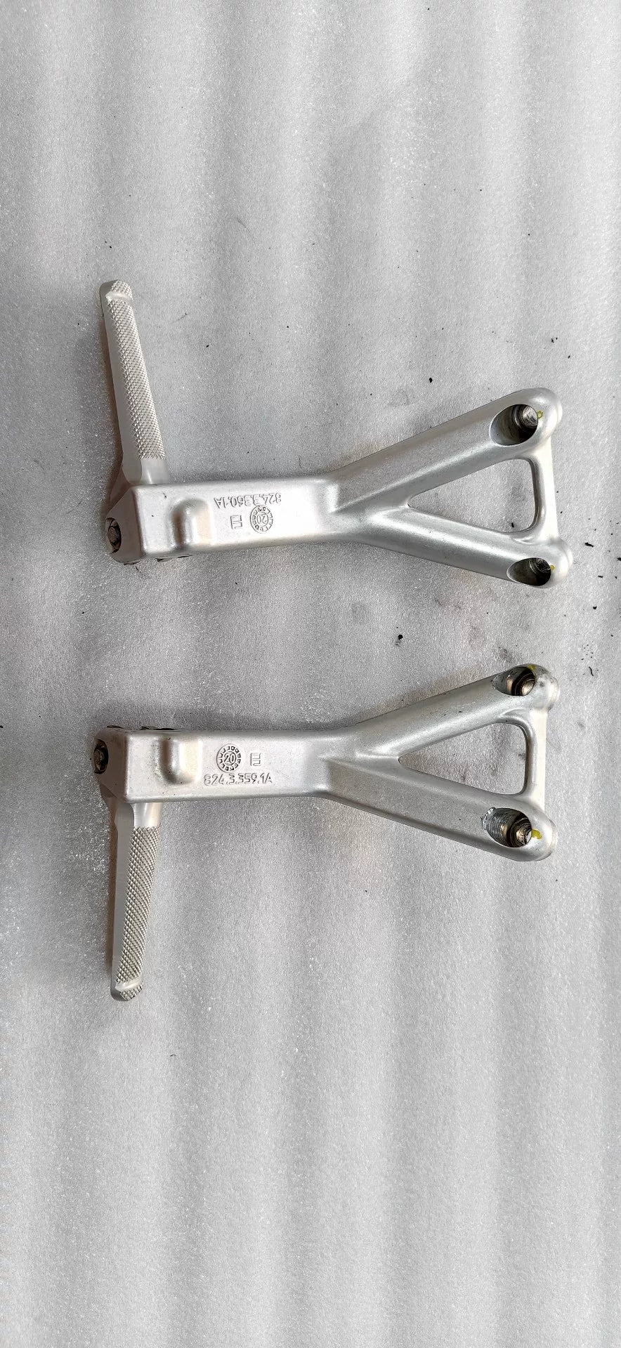 Ducati Panigale V4 footpeg bracket set, front view displaying left and right billet aluminum arms with pivot points