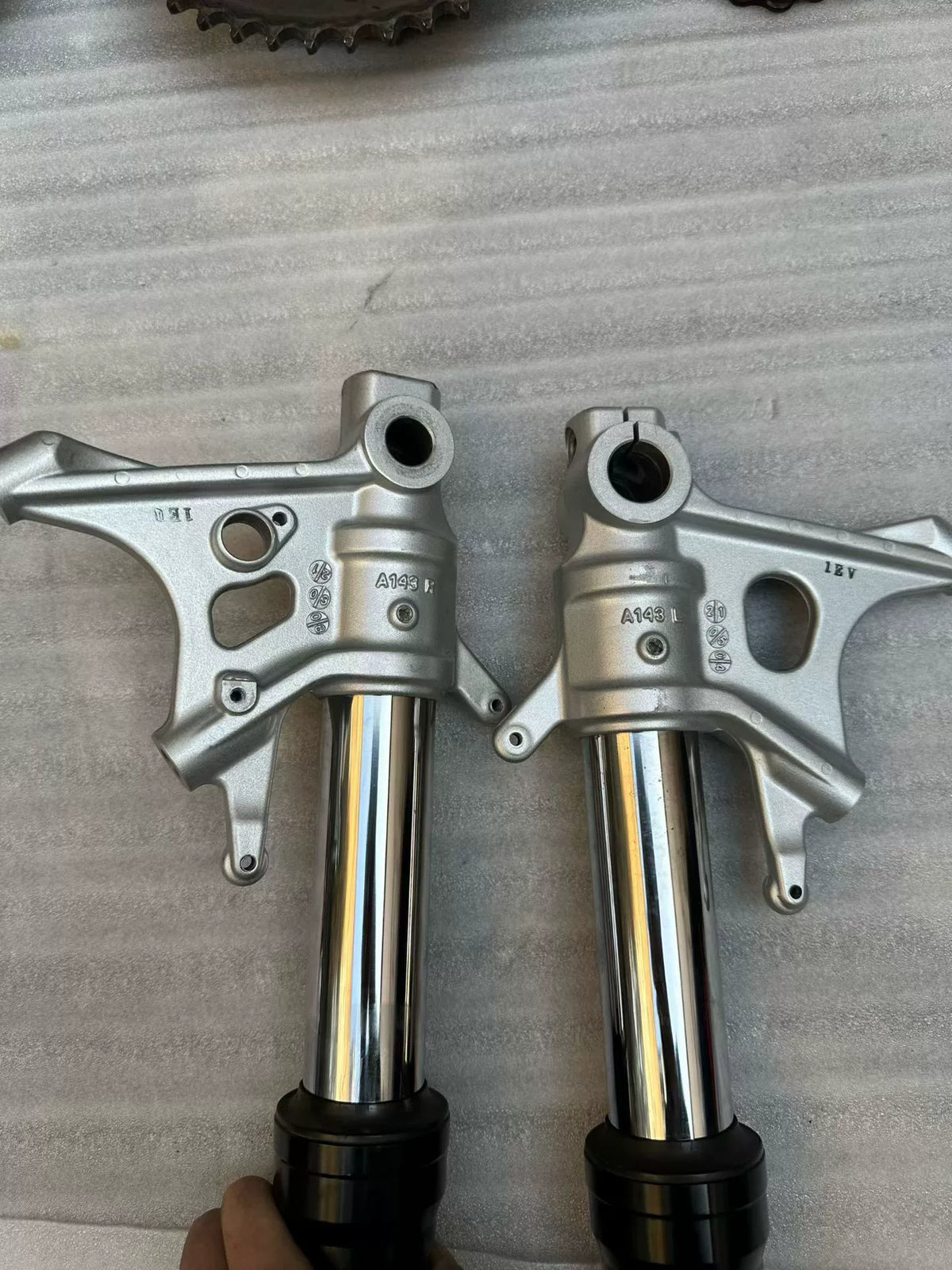 Aprilia Tuono 660 fork rod pair close-up top ends, machined metal finish, thread detail visible