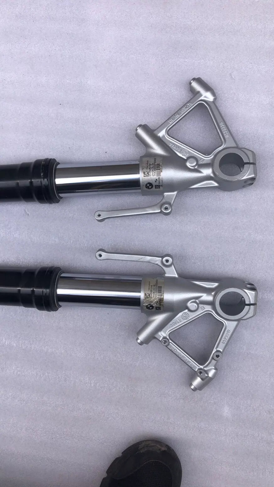 BMW S1000R fork leg pair, angled side view displaying full length of polished tubes and axle clamps