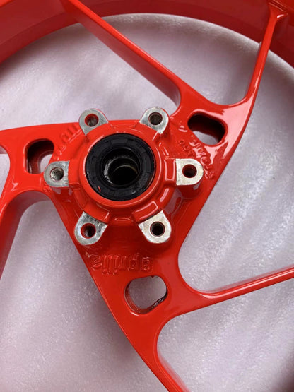 Detail of red RS660 front rim hub showing Aprilia branding, bearing seal and bolt holes