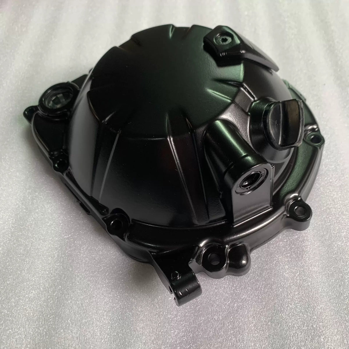 Black clutch cover for Kawasaki ZR900 Z900, angled side view of domed ribbed casing with mounting bolt holes