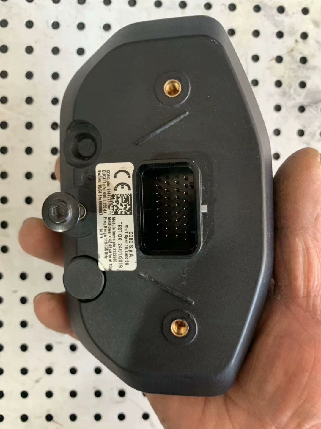Rear of Ducati Monster 797 instrument panel, COBO label, multi-pin connector, gold mounts, held in hand