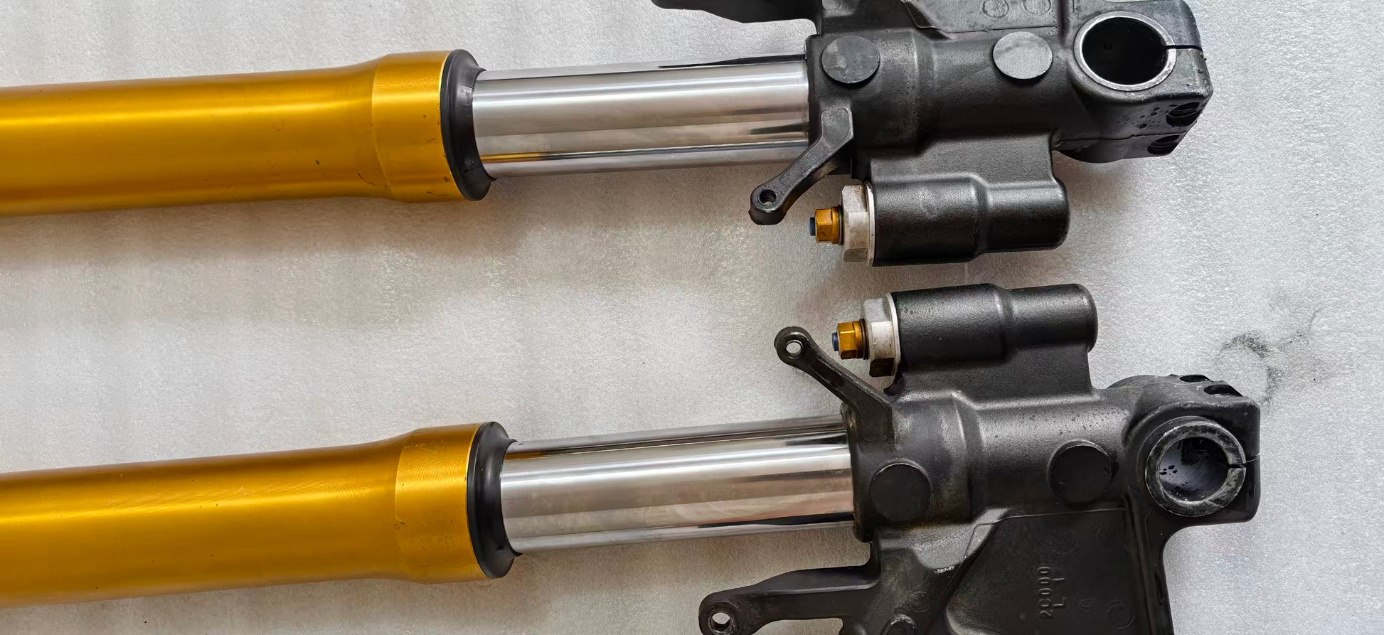 Close-up of YZF-R6 fork sliders, chrome tubes, gold uppers and black brackets with gold preload adjusters