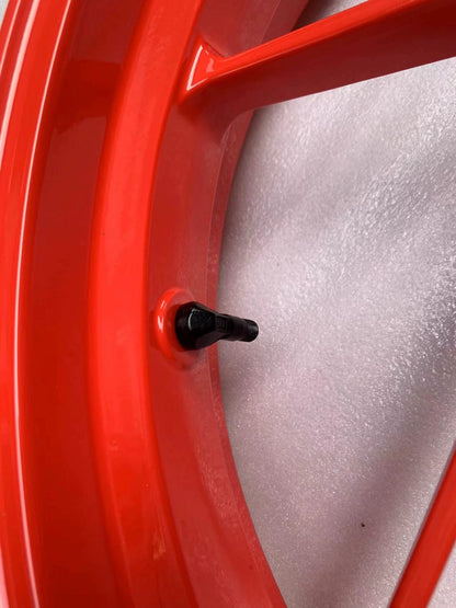 Macro view of black valve stem on red Aprilia RS660 front rim inner barrel