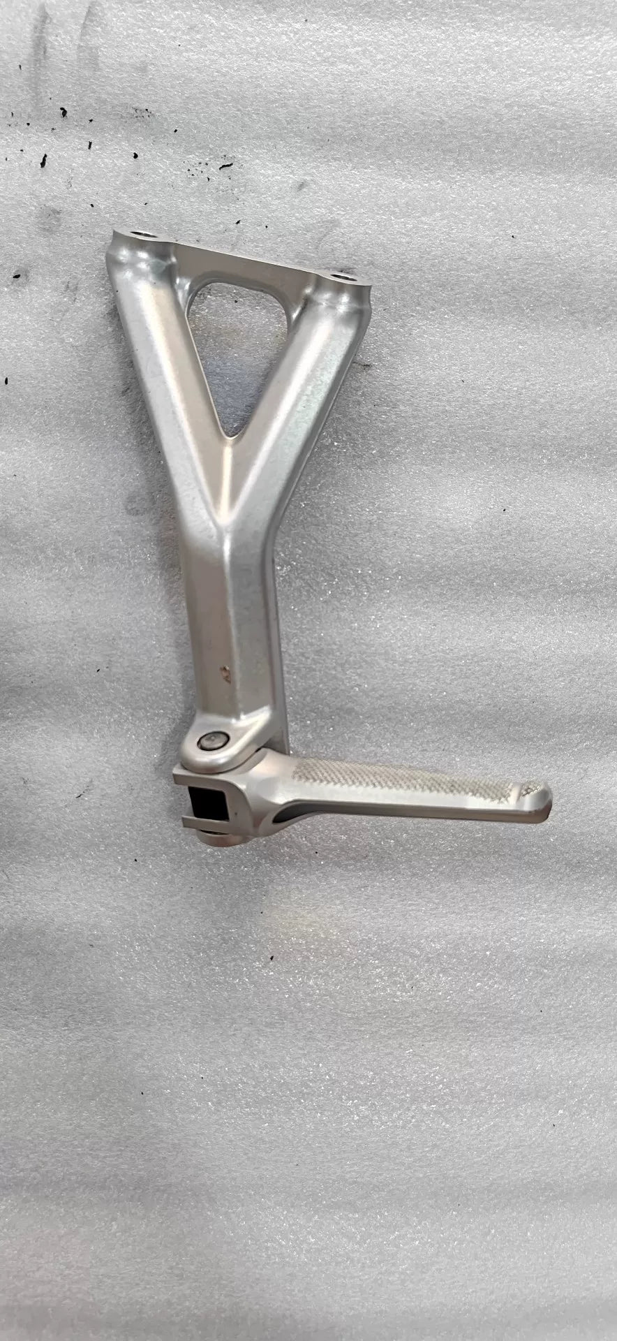 Panigale V4 rear sets bracket close-up showing CNC machined detail, anodized finish and precision drilled holes