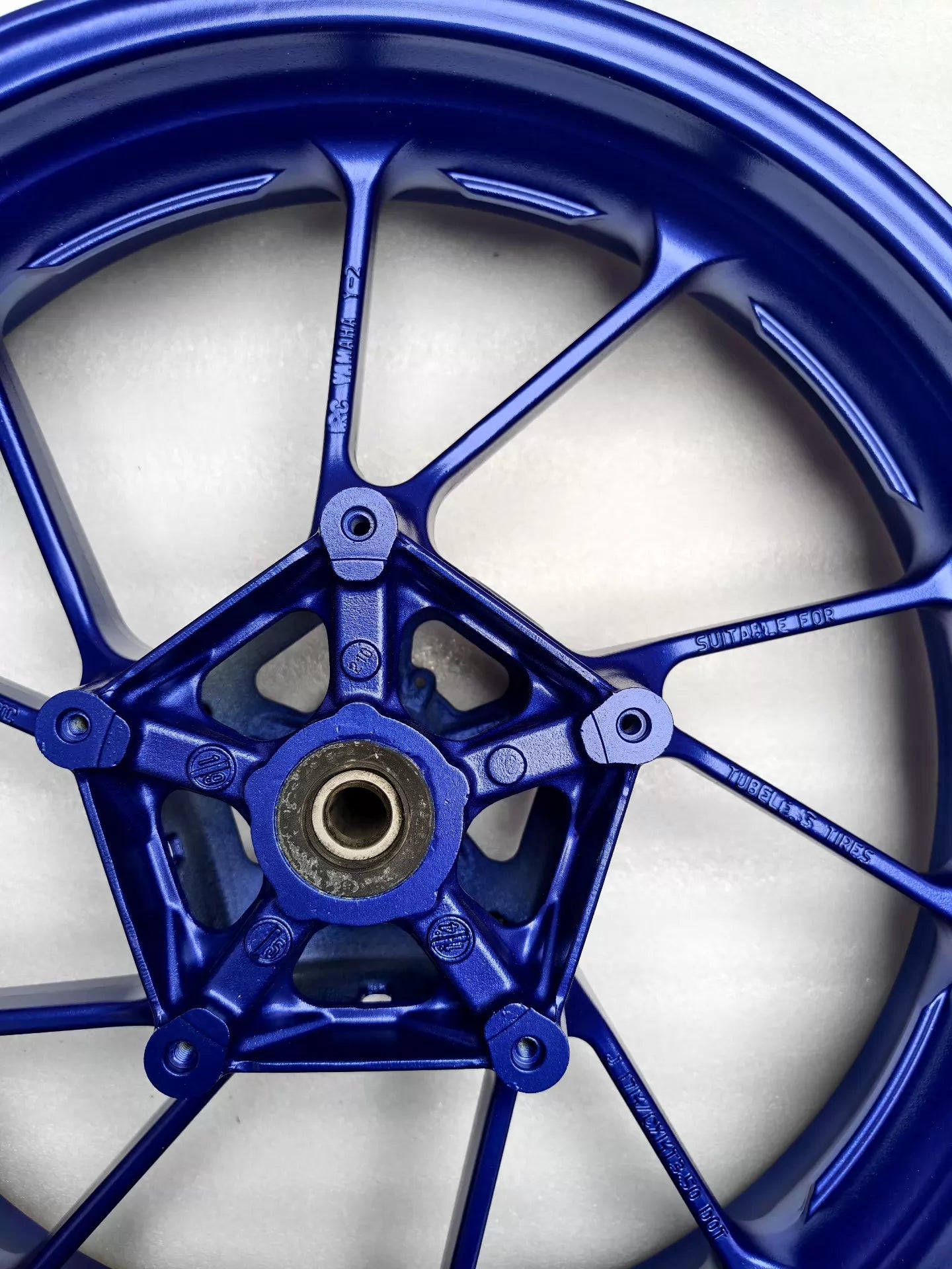 Close-up of blue cast wheel hub for Yamaha MT-07 FZ-07, showing bearing bore, valve stem and YAMAHA cast markings