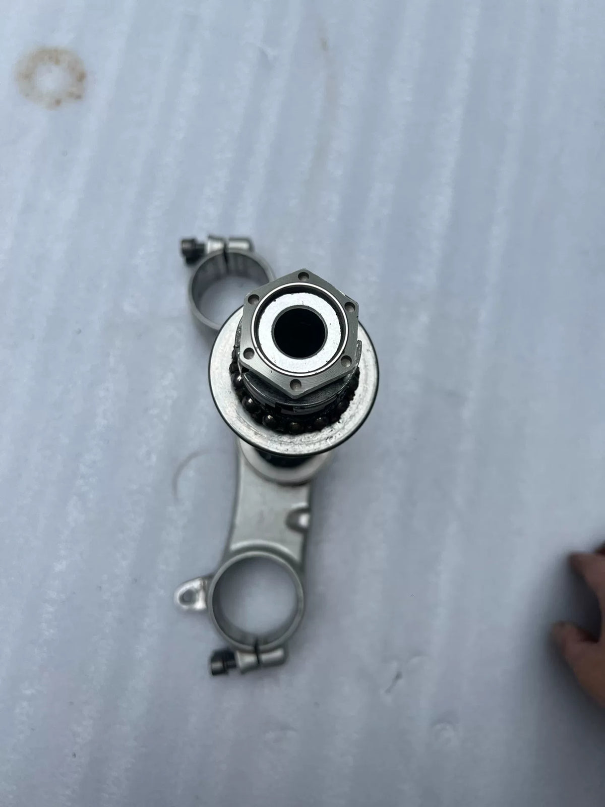 BMW S1000RR triple clamp angled view showing lower yoke with steering stem and precision machining detail