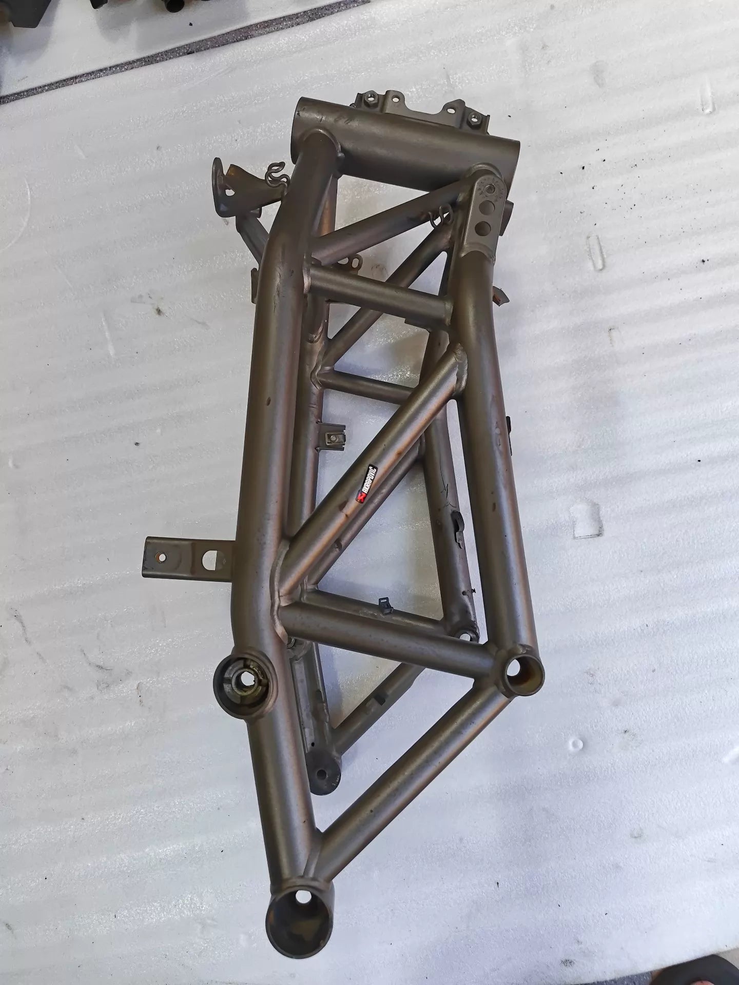 Angled side view of grey trellis frame for Ducati MTS1200, Akrapovic sticker, pivot bearing seats, used