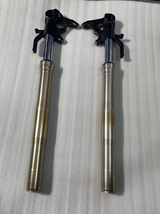Complete pair of Kawasaki Z1000 front forks upright on white foam, gold lowers, black axle brackets, chrome stanchions
