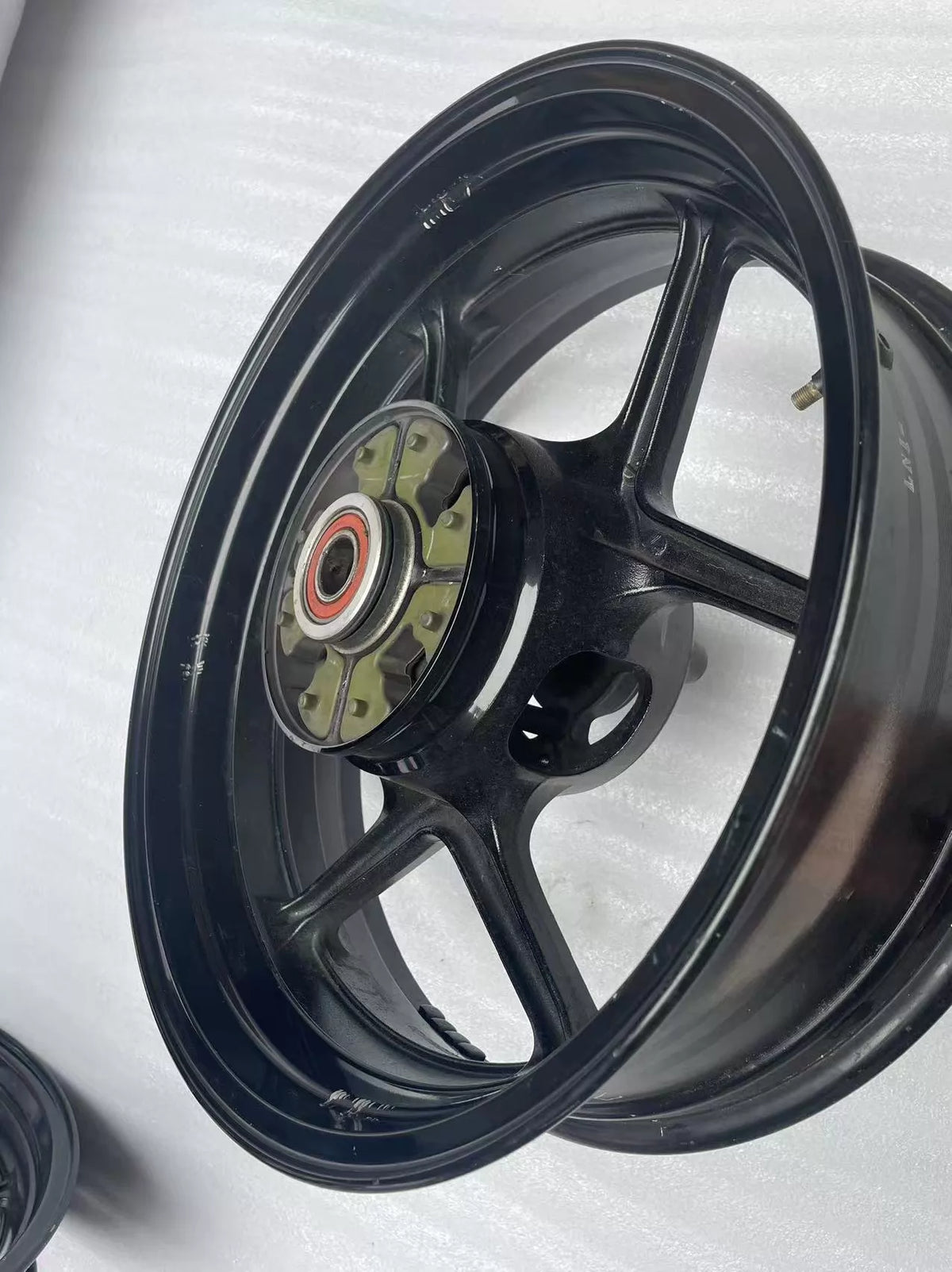 Kawasaki ZX-6R rear wheel rim WHEEL-ASSY gloss black, angled view displaying rim width and spoke pattern
