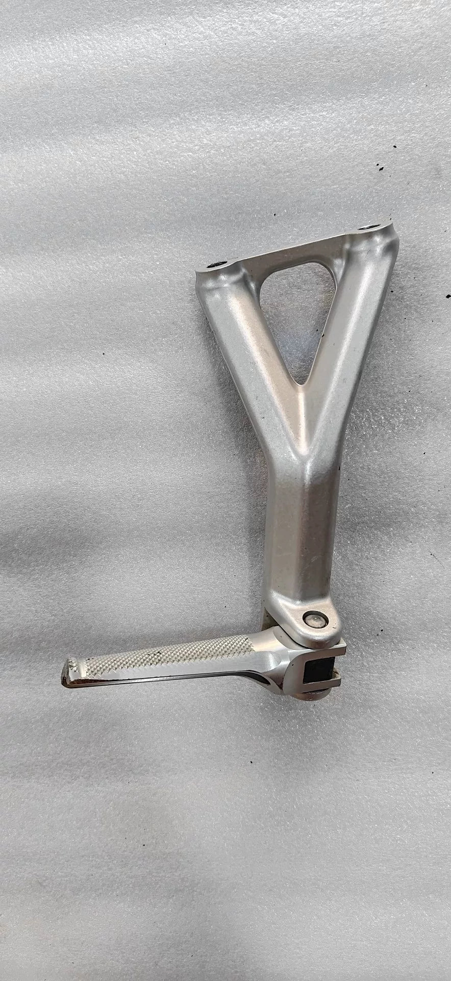 Ducati Panigale V4 footpeg bracket underside view revealing welded joints, bolt holes and raw aluminum finish