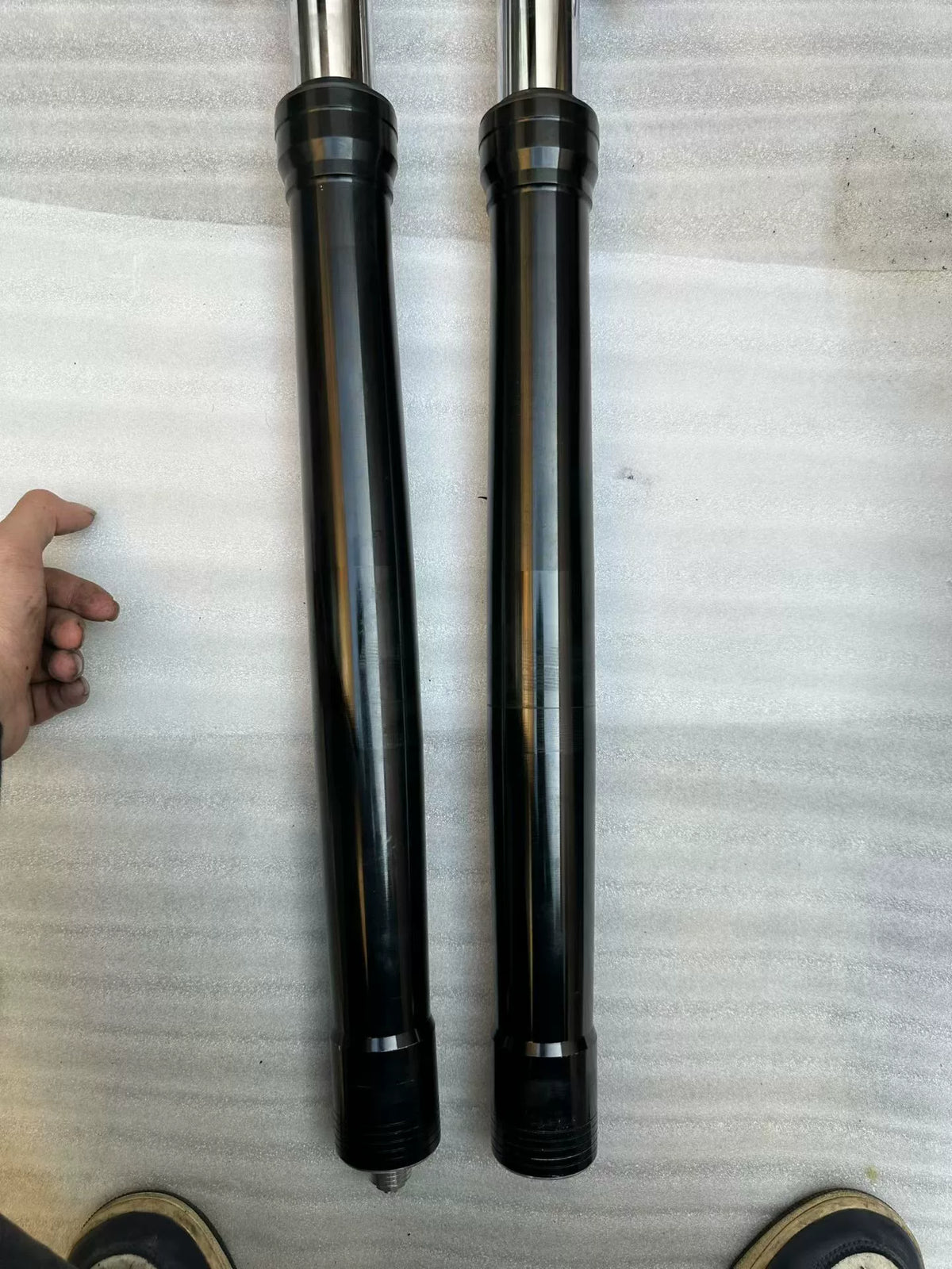 Aprilia Tuono 660 fork rod pair laid flat, full length comparison view, straight undamaged shafts