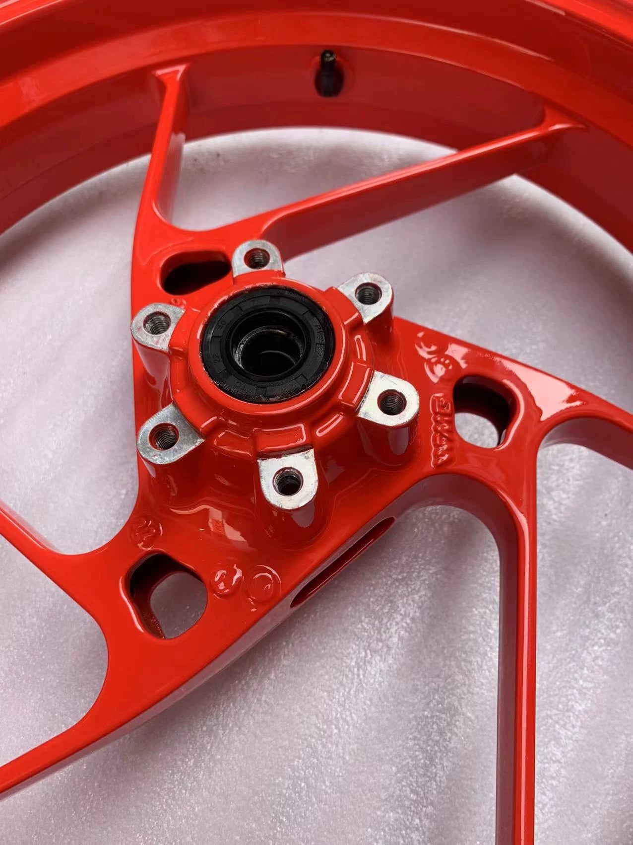 Close-up of red RS660 front rim hub, wheel bearing seal and five bolt mounts, angled view