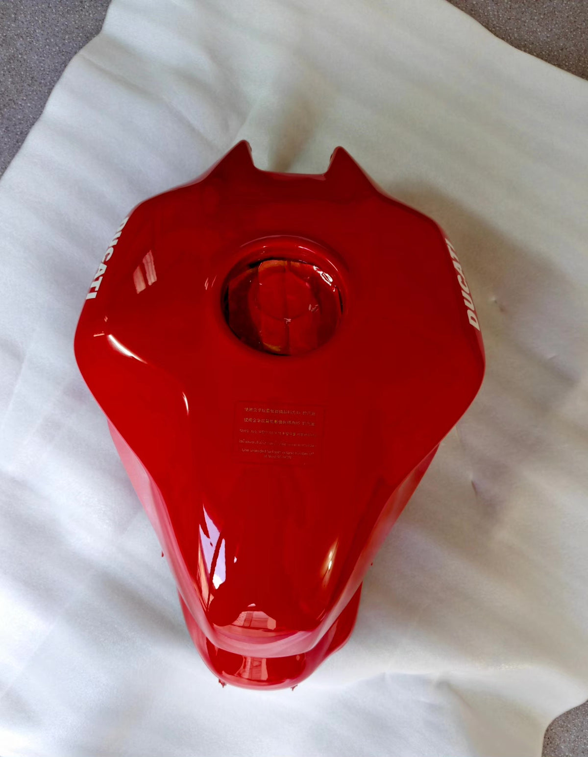 Red fuel tank for Ducati SuperSport 939, underside view showing tank mounts and internal hardware