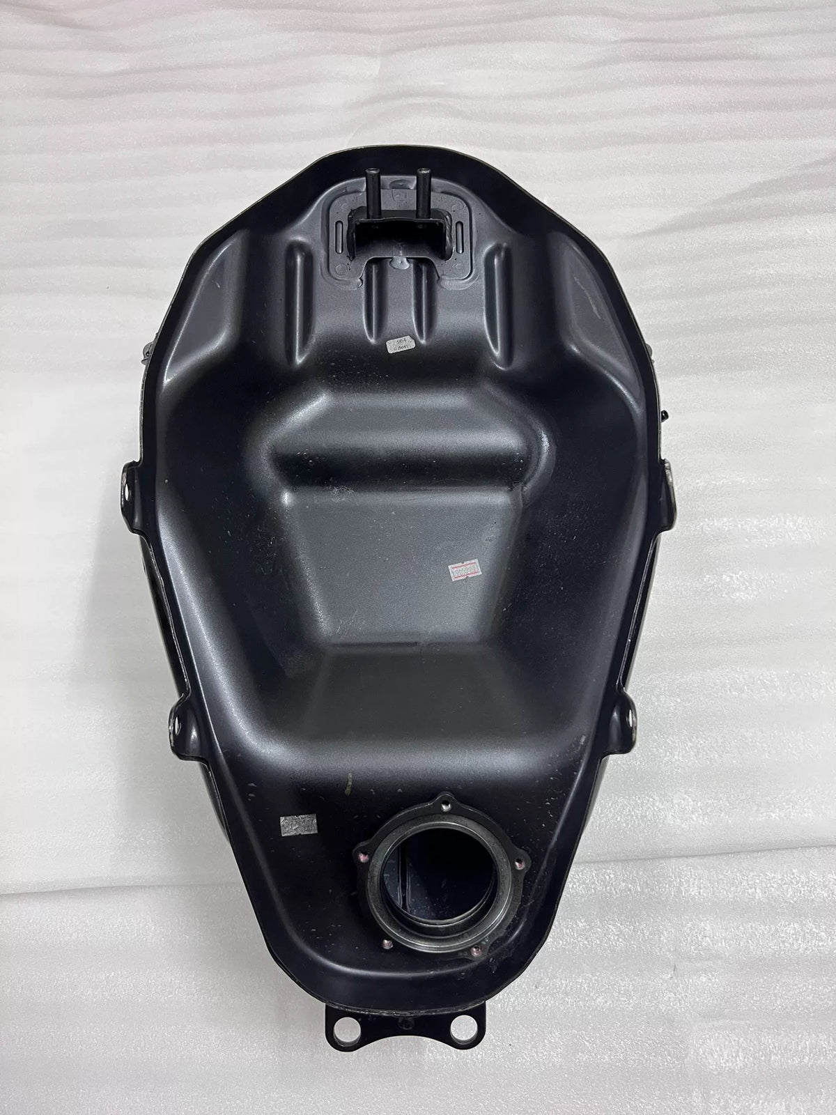 Kawasaki Ninja 400 fuel tank underside view revealing petcock port and frame mounting hardware