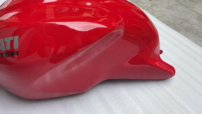 Close-up of red Ducati Monster fuel tank right side showing knee recess and DUCATI decal