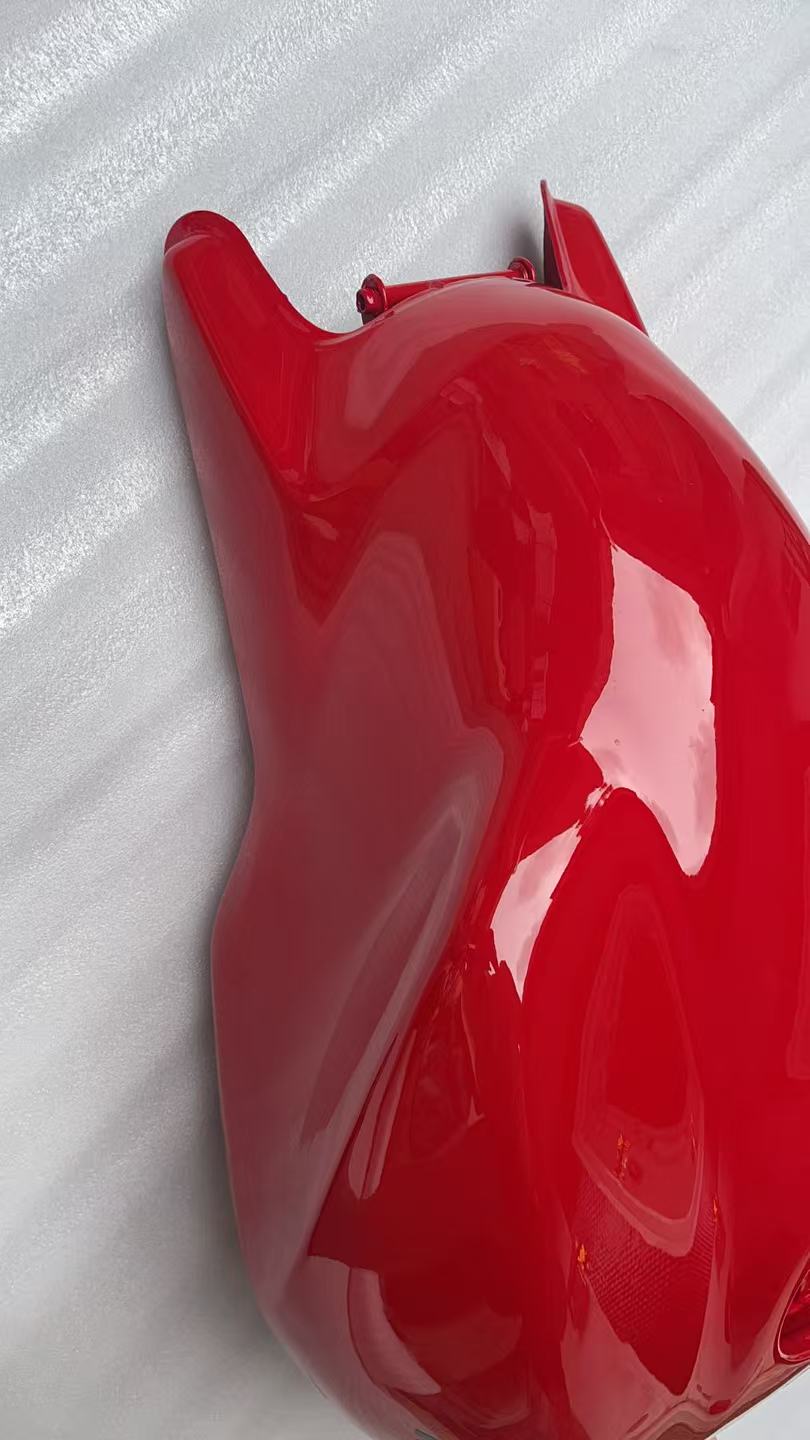 Angled side view of glossy red Ducati Monster 821 fuel tank showing curved contour and front mount