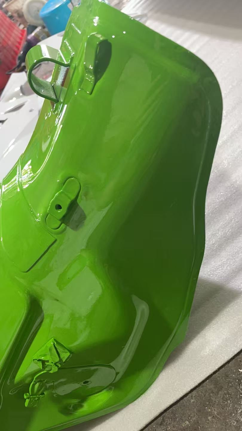 Underside rear view of green ZX10R fuel tank showing mounting bracket, hinge loop and pump lugs