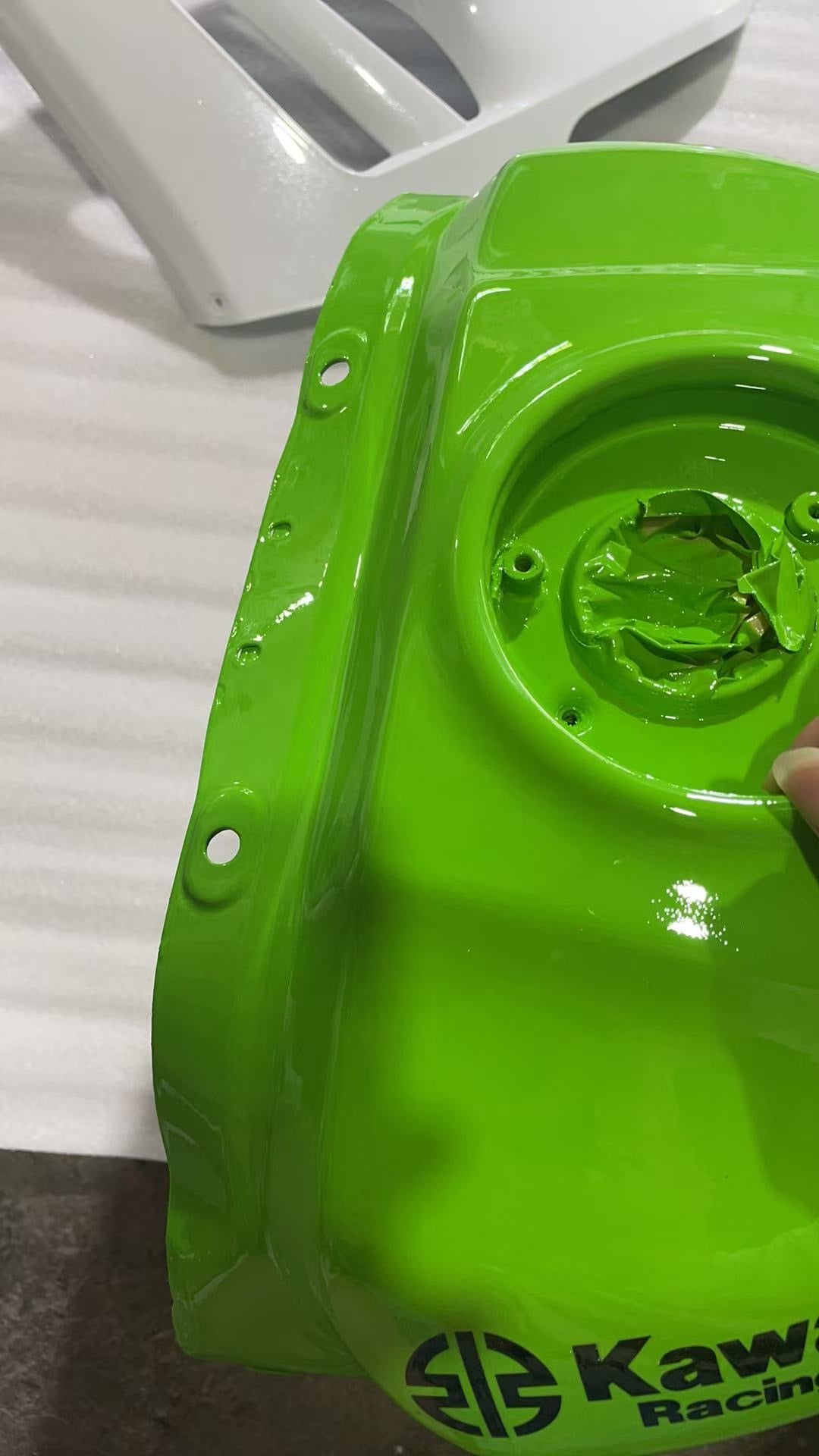 Rear underside of green ZX10R fuel tank, fuel pump opening ring with bolt holes and paint-covered edges