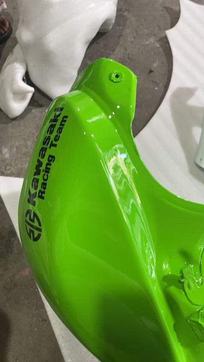 Front left corner of green ZX10R tank showing Kawasaki Racing Team decal and front mount bolt hole