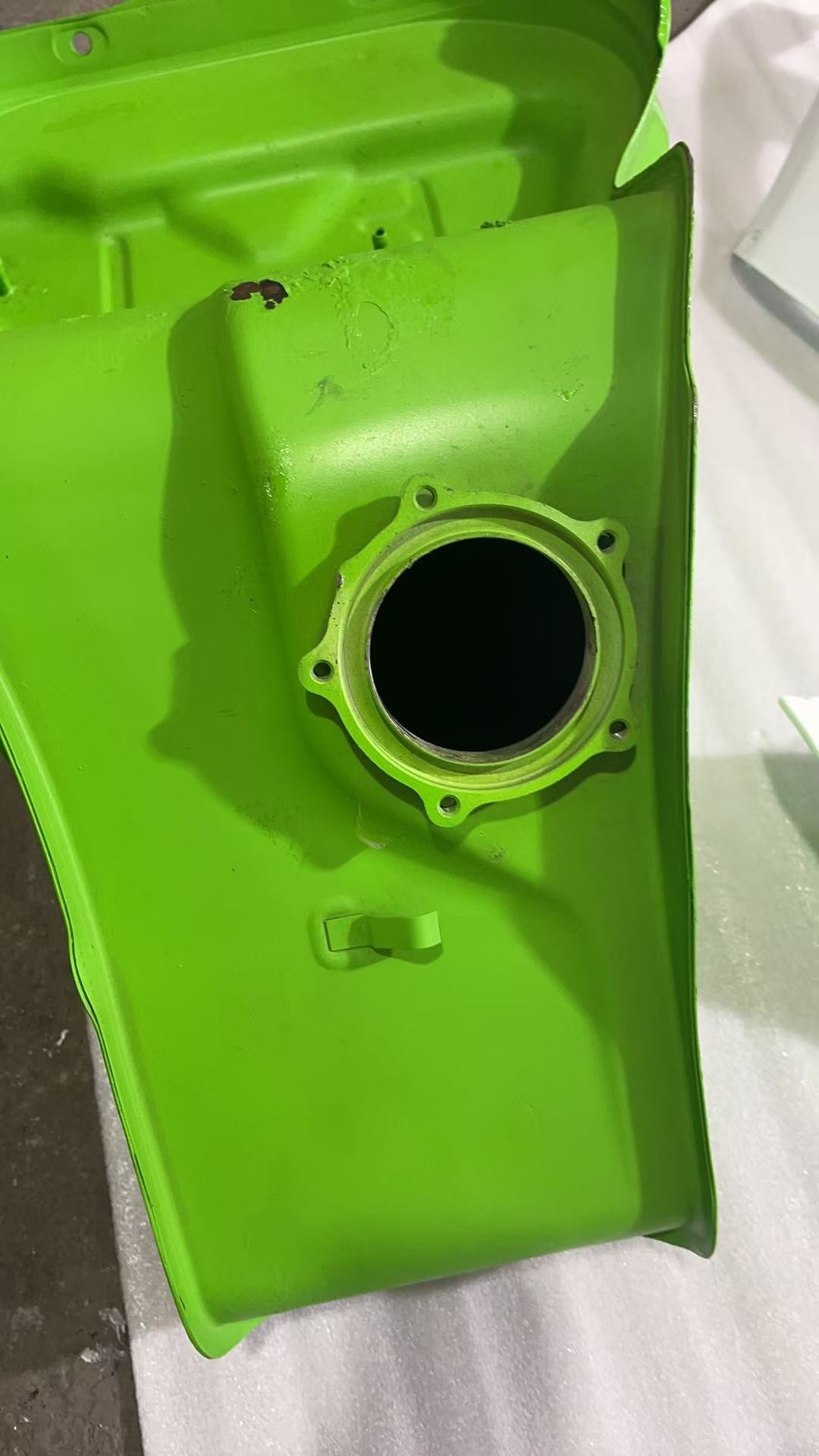 Underside of green ZX10R fuel tank with fuel pump flange bore, bare metal ring and small rust spot