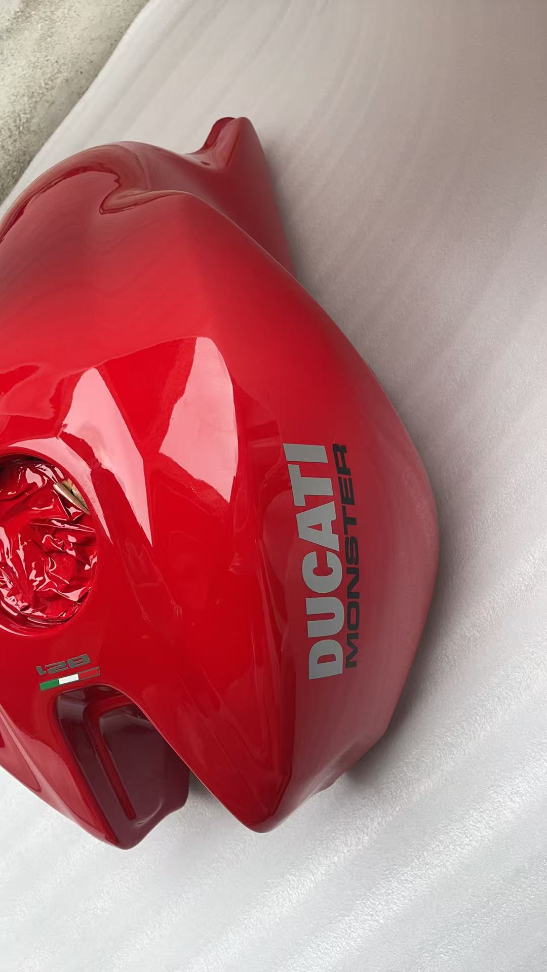 Left side of red Ducati Monster 821 fuel tank with DUCATI MONSTER decal and 821 Italian flag badge