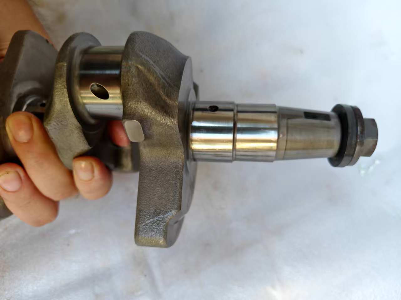 Side Yamaha MT-09 crankshaft held showing tapered nose end, oil seal, splined shaft and polished main journal