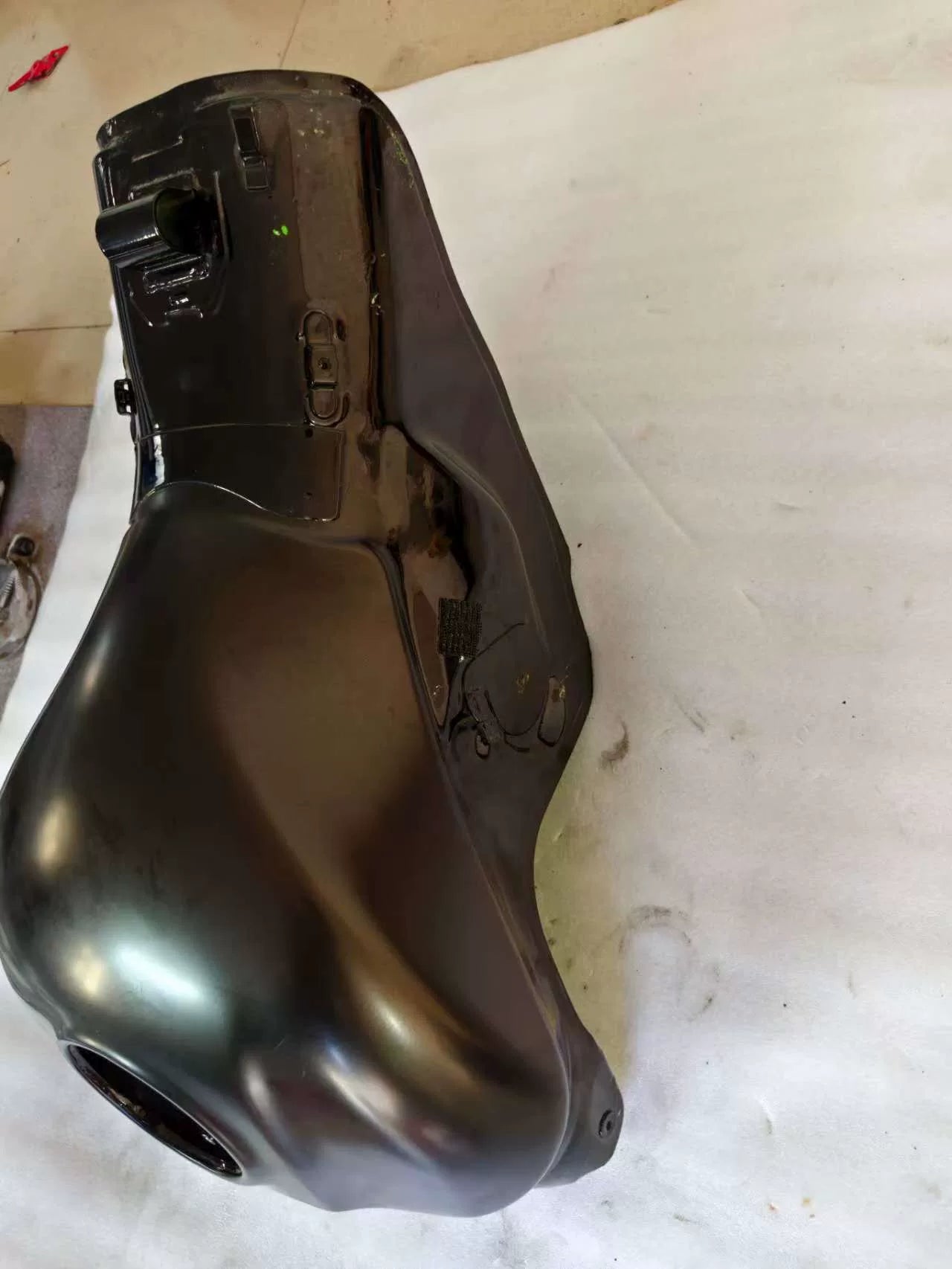 Angled overhead view of black Kawasaki ZX10R fuel tank showing front mounting brackets and light surface scuffs