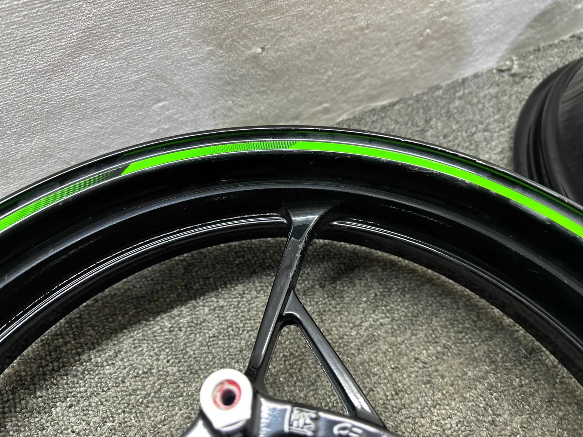 Kawasaki Ninja 650 front wheel hub bearing repainted gloss black green stripe close-up
