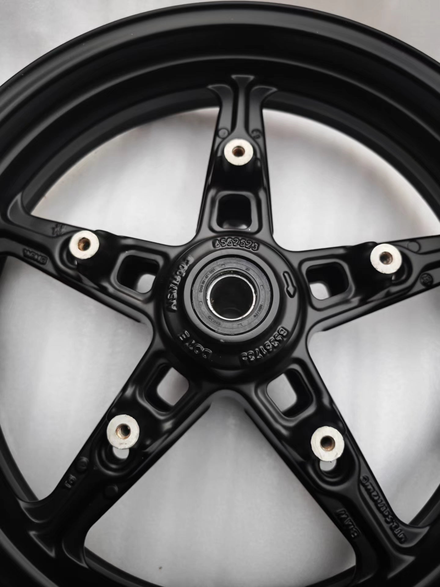 Close-up of black 5-spoke cast front rim hub with bearing and part number for BMW R NineT
