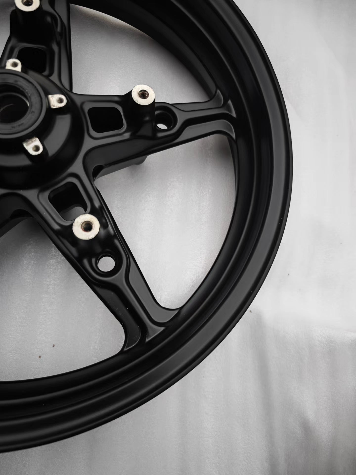 Angled view of matte black cast front wheel rim edge and spoke for BMW R NineT