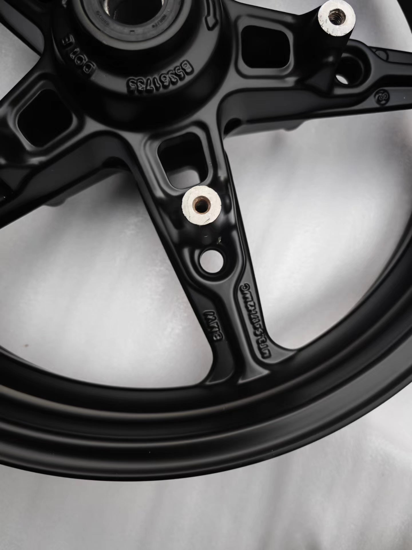 Detail of black cast front rim hub, cast markings and spoke bolt holes, BMW R NineT
