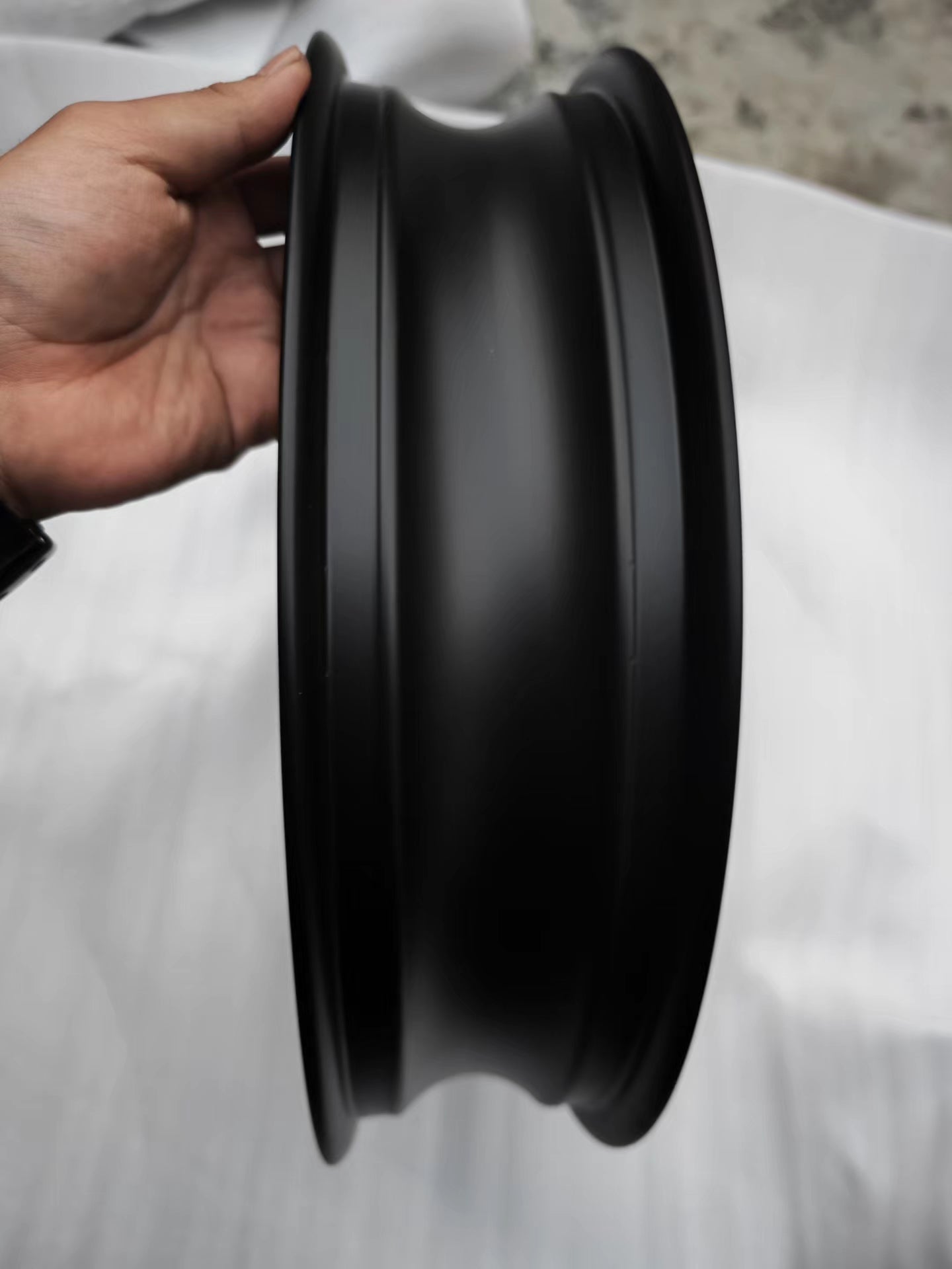 Side profile of matte black cast front rim held in hand showing barrel, BMW R NineT