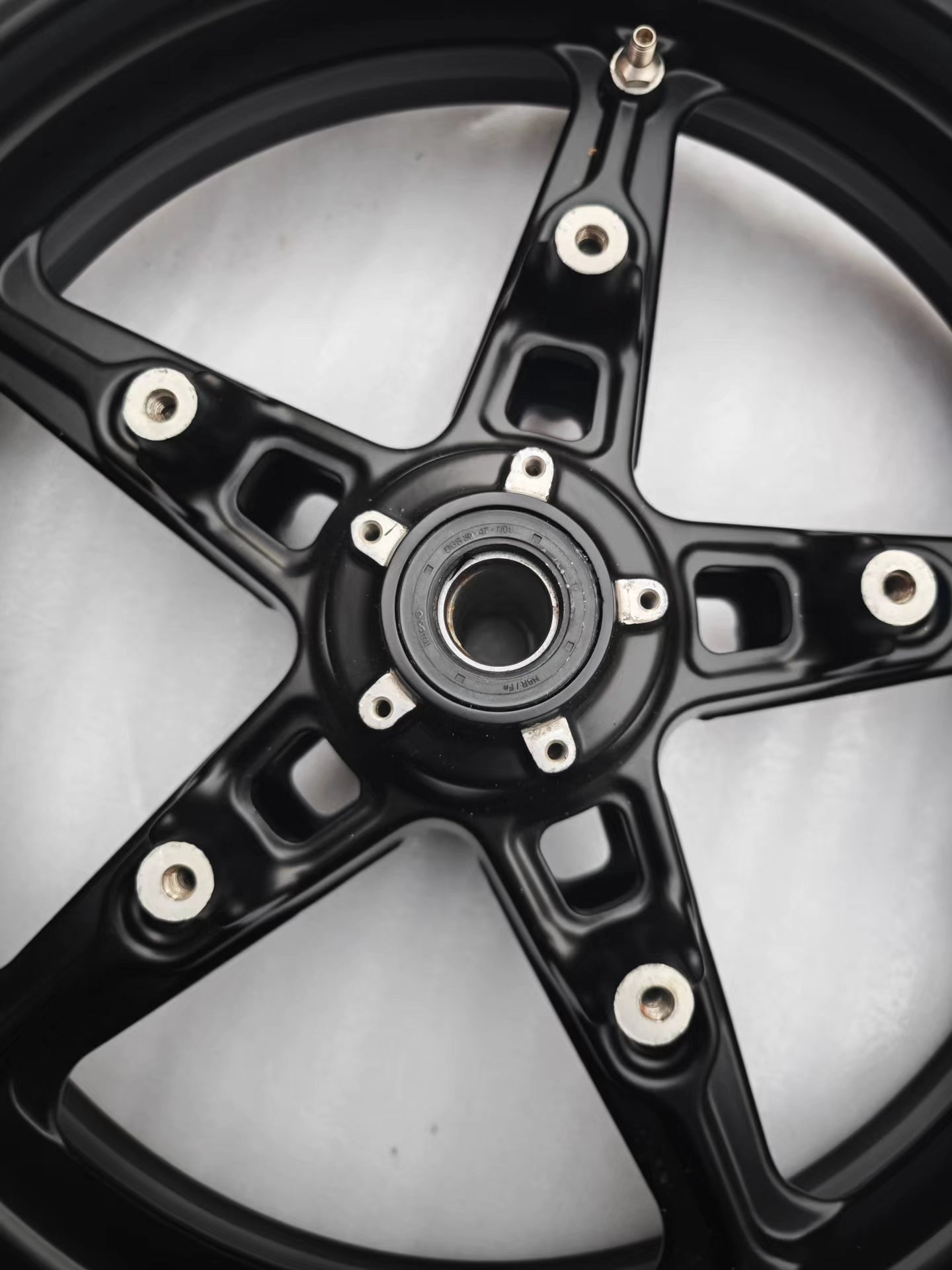 Angled close-up of black 5-spoke cast front wheel hub and bearing, BMW R NineT