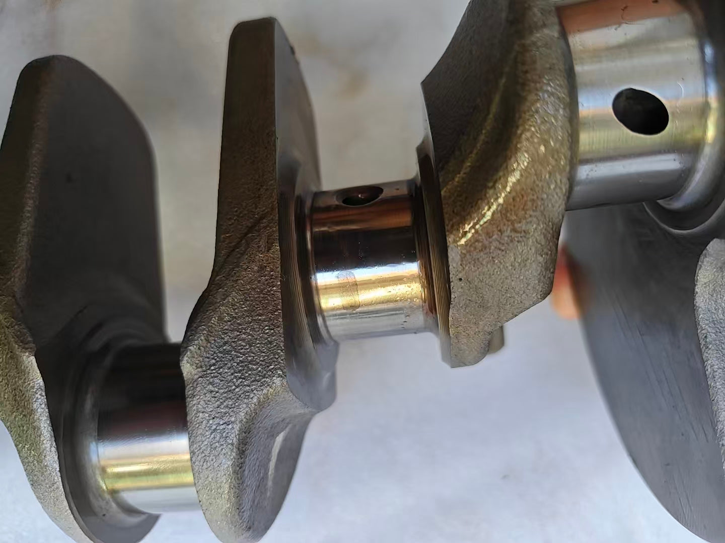 Close-up of two Yamaha MT-09 crankshaft journals and cast webs, polished pins with oil holes, light surface staining