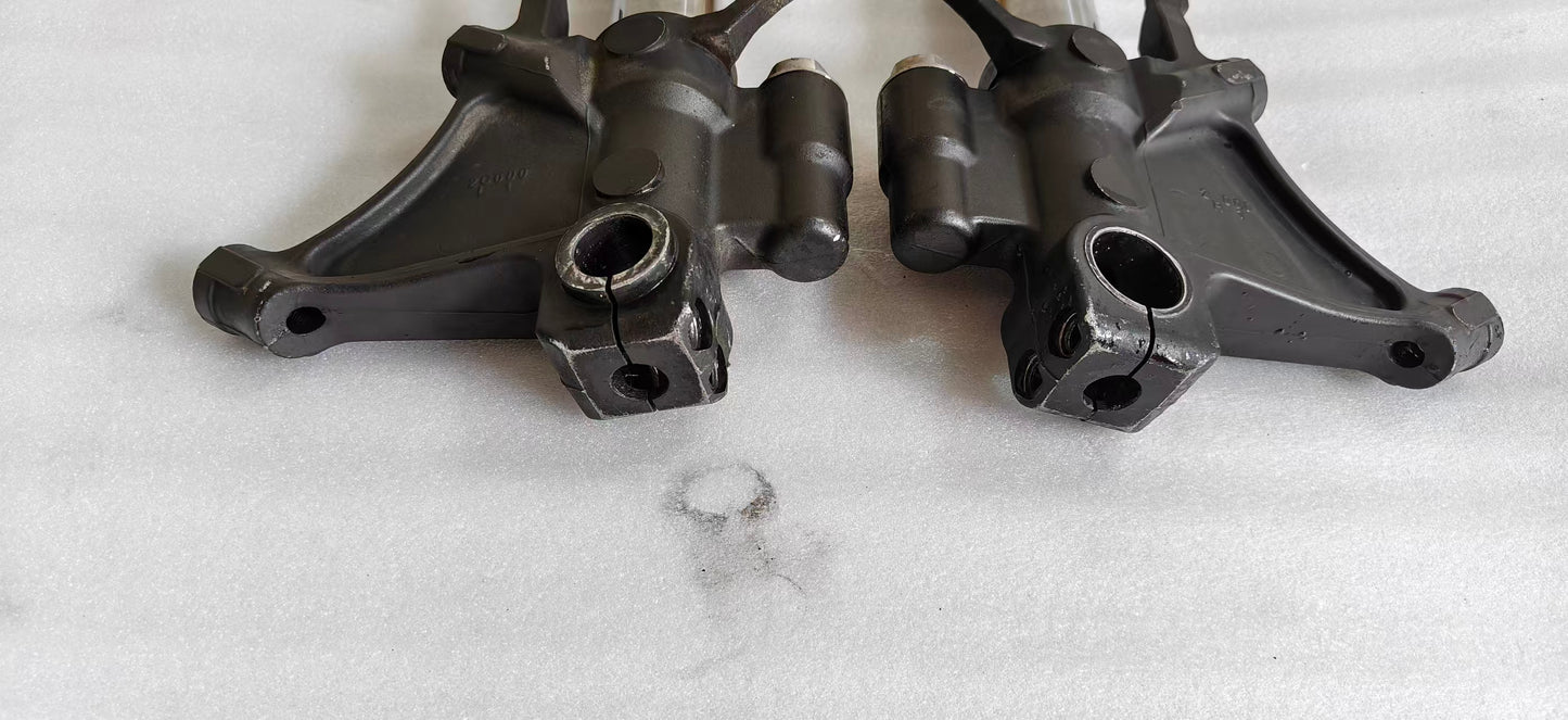 Close-up of two YZF-R6 fork lower brackets, black cast axle clamps and caliper mounts, front detail