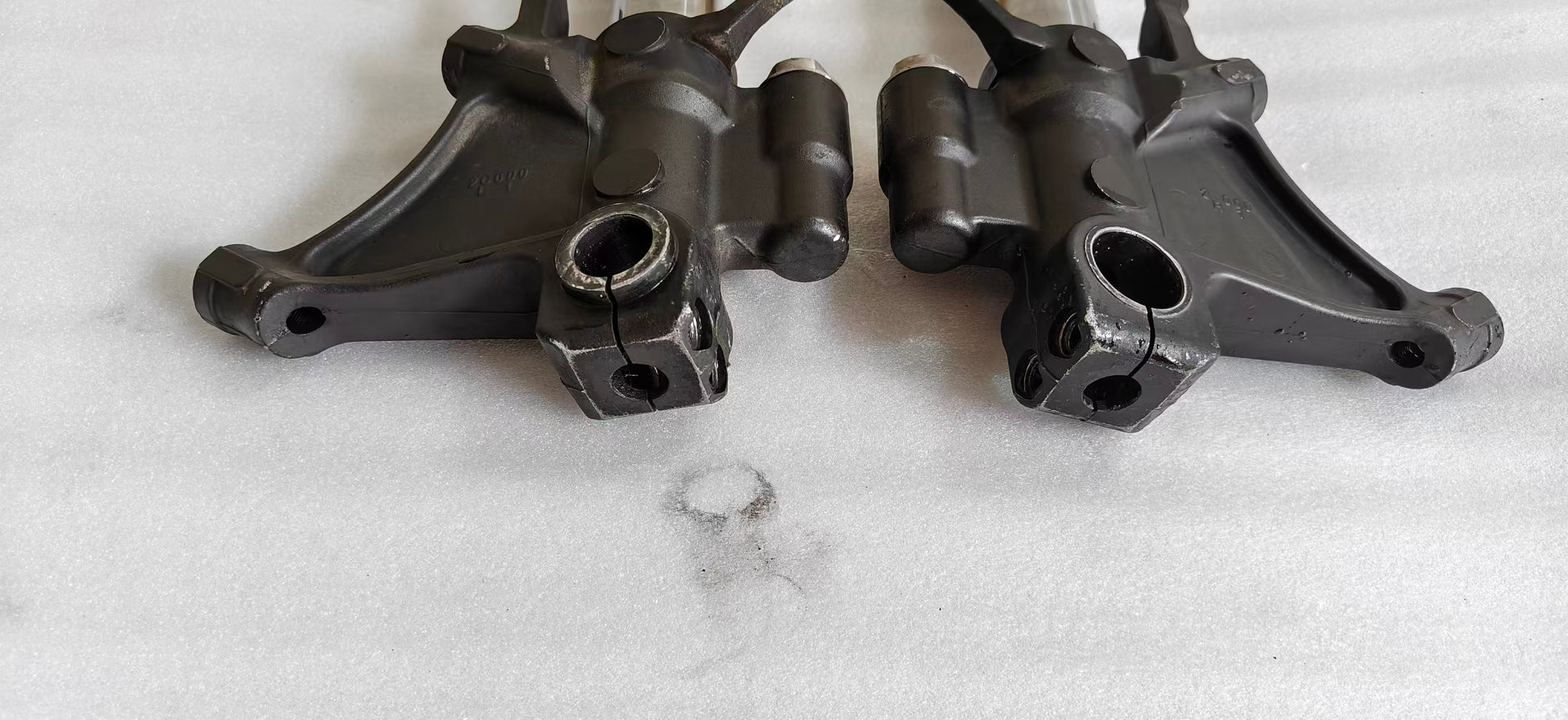 Close-up of two YZF-R6 fork lower brackets, black cast axle clamps and caliper mounts, front detail
