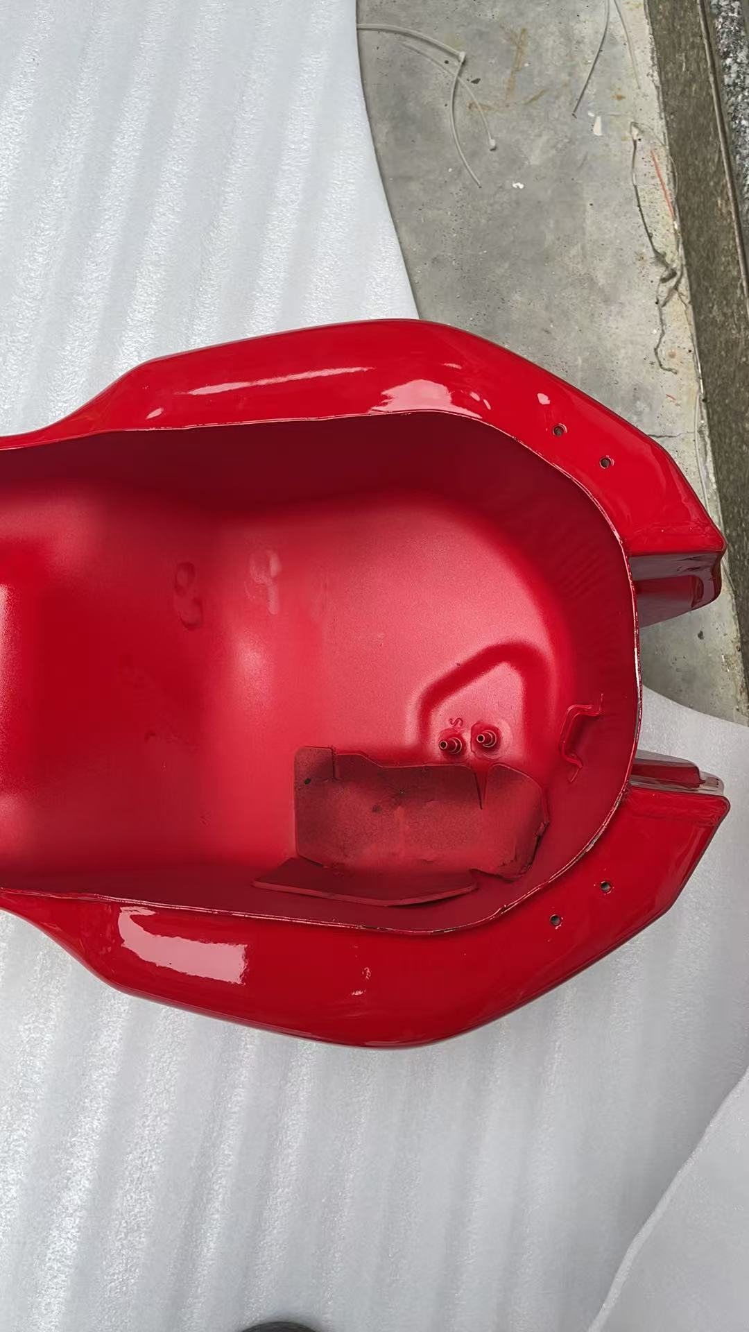Underside cavity of red Ducati Monster 821 fuel tank showing fuel pump seals, mounting holes and bracket