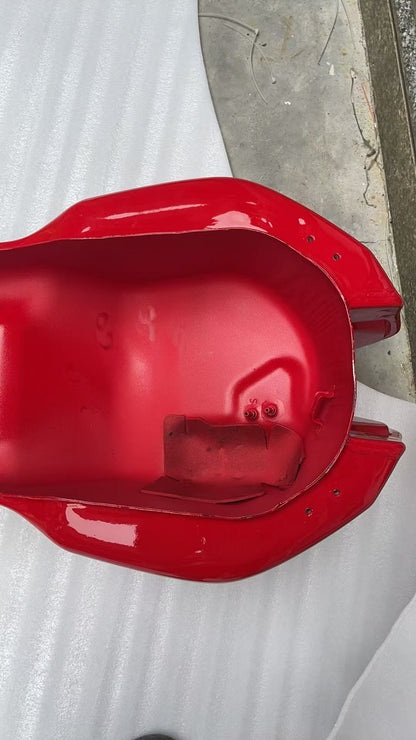 Underside cavity of red Ducati Monster 821 fuel tank showing fuel pump seals, mounting holes and bracket