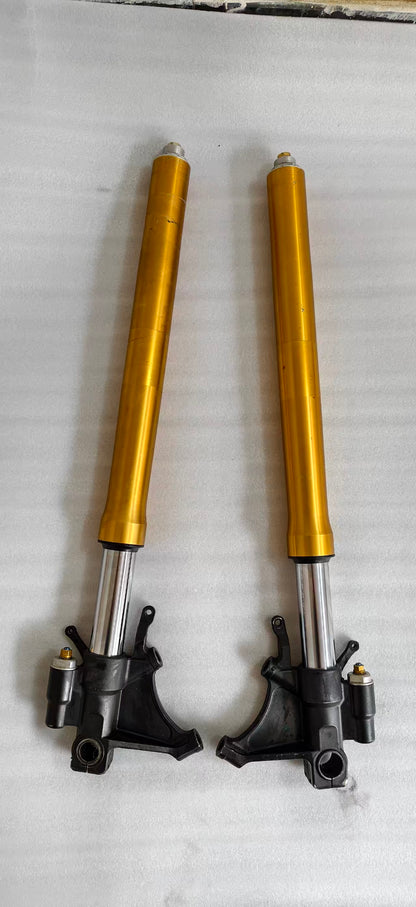 Pair of gold Yamaha YZF-R6 front fork tubes with black lower brackets, laid vertically on white cloth